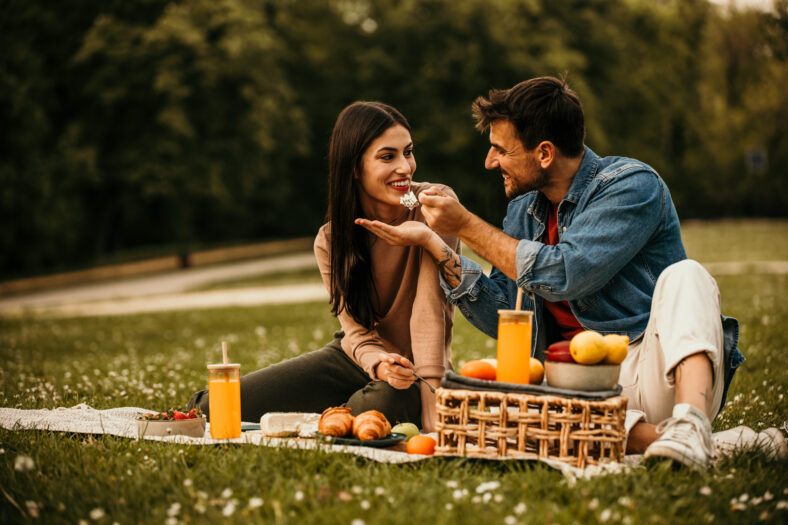 Two people bonding over snacks and beverages on a cozy picnic blanket in the park