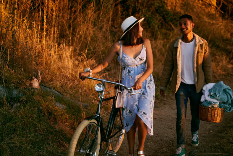 Romantic, happy and couple on a picnic in a park for a date, holiday and love in Indonesia. Travel, smile and man and woman walking in nature for romance, peace and relax with food during sunset.