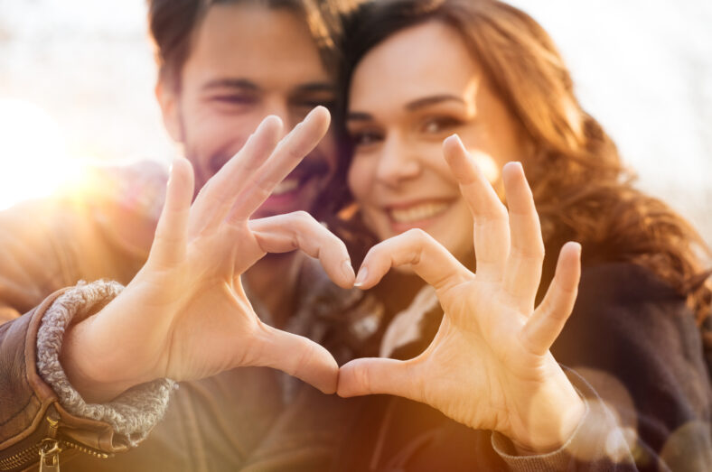 Closeup of couple making heart shape with hands