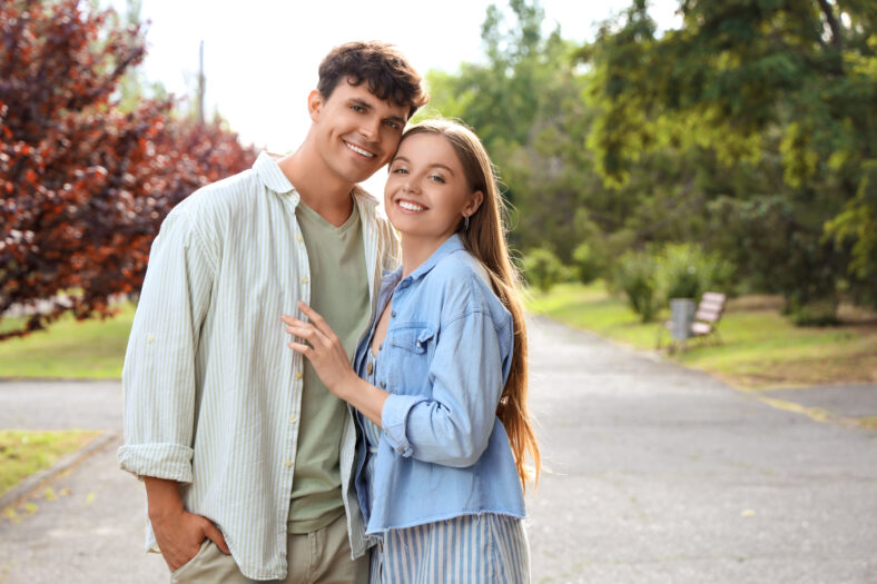 Beautiful young happy couple hugging in summer park