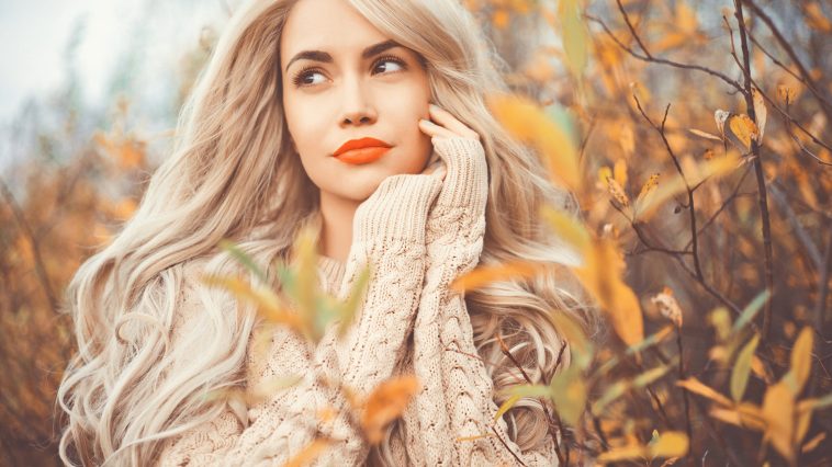 Outdoor fashion photo of young beautiful lady surrounded autumn leaves