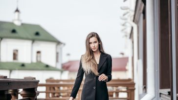 Business girl in a black suit against the background of the city. Near the office buildings.