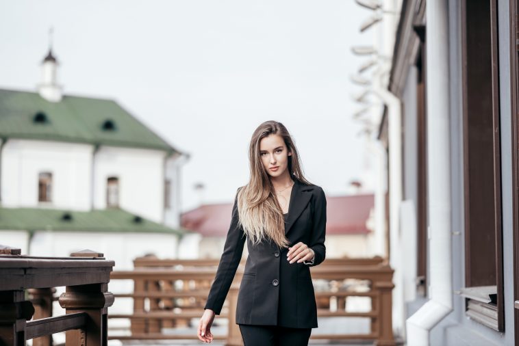 Business girl in a black suit against the background of the city. Near the office buildings.