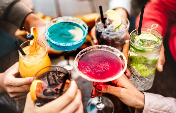 People hands toasting multicolored fancy drinks