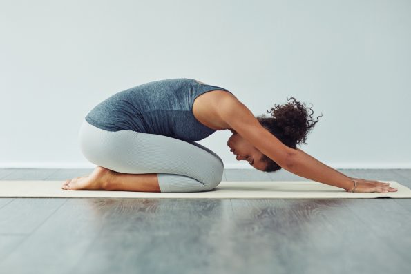 Yoga, child pose and woman stretching on mat for wellness, workout and fitness in gym studio. Healthy body, meditation and female person doing pilates exercise for balance, flexibility and wellbeing.