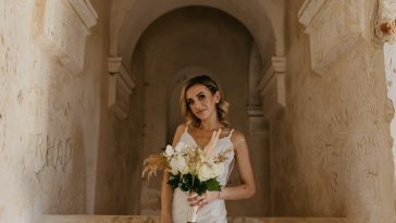 A caucasian bride posing in the church and holding a bouquet of white flowers