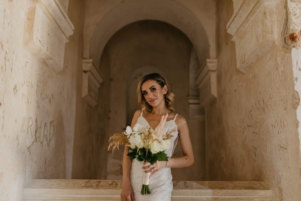 A caucasian bride posing in the church and holding a bouquet of white flowers