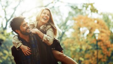 Young smiling couple enjoying fall in the park.