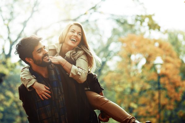 Young smiling couple enjoying fall in the park.