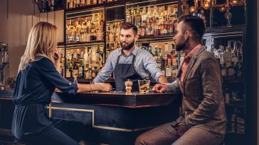 Stylish brutal bartender serves an attractive couple who spend an evening on a date.