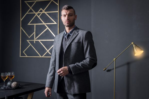 Portrait of stylish handsome business man in luxury apartment. Businessman in dark interior. man in fashionable business gray suit in house. wine on table and night lamp in house of rich man