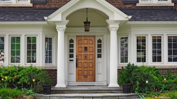 elegant wooden front door of large suburban house with gabled portico