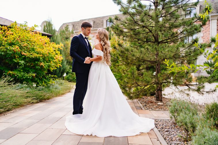 happy newlyweds. the groom and the blonde bride in traditional wedding clothes in a park. wedding fashion and organization of a holiday in the summer in the fresh air.