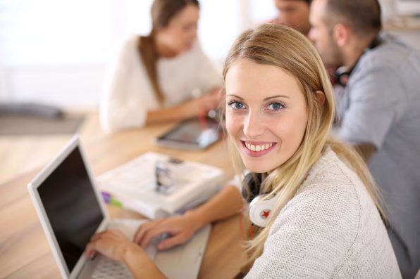 Student girl sitting in class and working on laptop