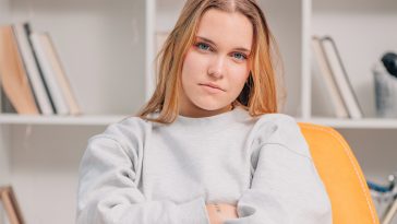 portrait of blue eyed blonde young woman or student at home