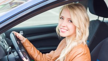 Beautiful happy young girl sitting in her car