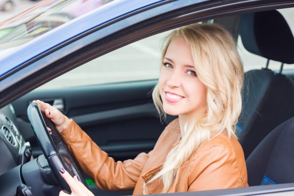 Beautiful happy young girl sitting in her car