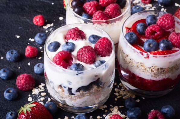 yogurt with oatmeal , blueberries , raspberries and strawberries on stone background