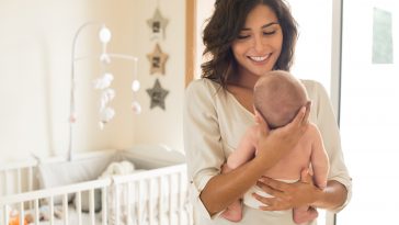 Young mother holding her baby in the bedroom