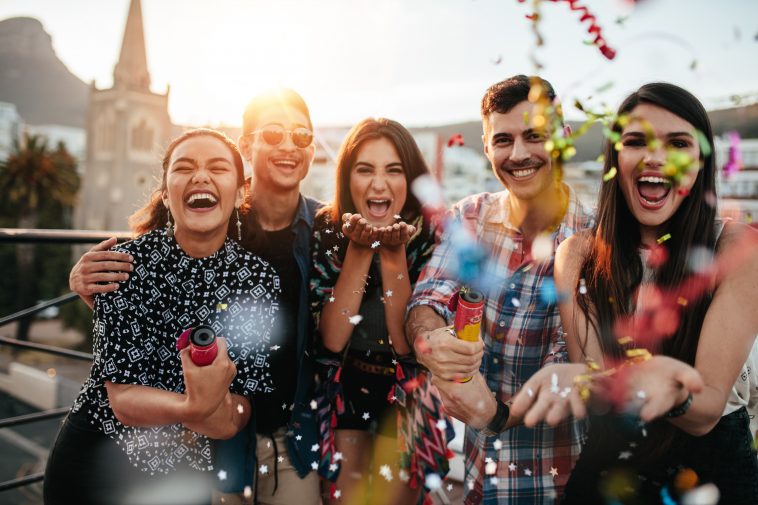 Group of friends enjoying party and throwing confetti. Friends having fun at rooftop party.