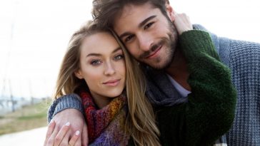 Portrait of beautiful young couple in love in a cold winter on the beach.