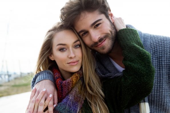 Portrait of beautiful young couple in love in a cold winter on the beach.