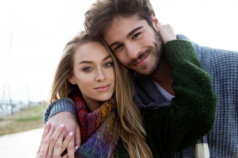 Portrait of beautiful young couple in love in a cold winter on the beach.