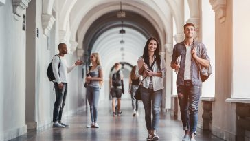 Multiracial students are walking in university hall during break and communicating.