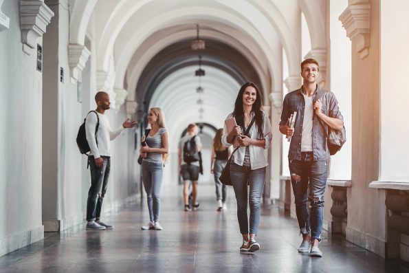 Multiracial students are walking in university hall during break and communicating.