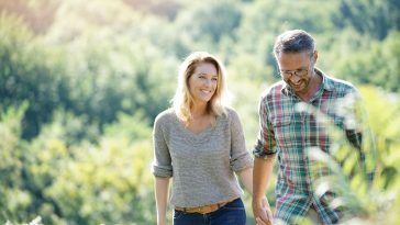 Happy mature couple walking in countryside on sunny day