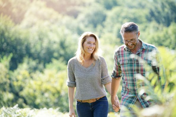 Happy mature couple walking in countryside on sunny day