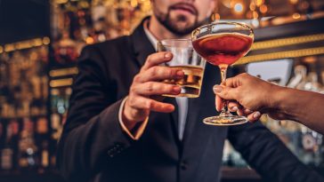 Cropped image of an attractive couple is spending the evening in a romantic setting, drinking wine at the bar counter.