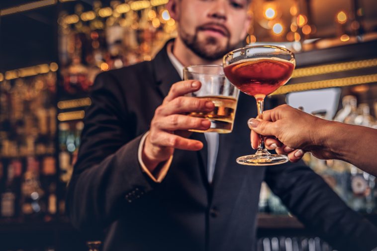 Cropped image of an attractive couple is spending the evening in a romantic setting, drinking wine at the bar counter.