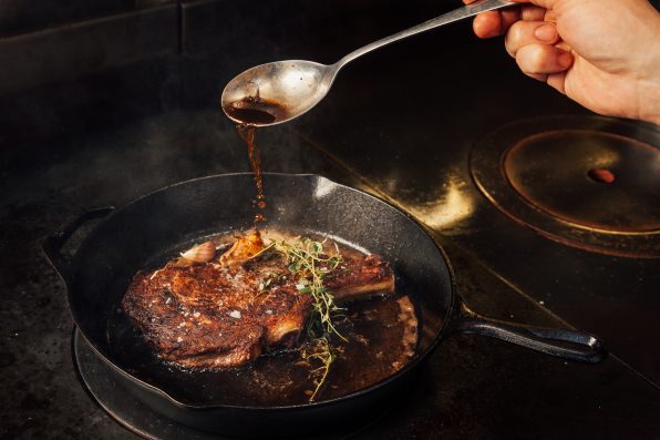 Cooking steak in a cast iron pan in a fine dining restaurant.