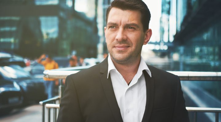 handsome man in suit on the street. Outdoors portrait of a businessman smiling in the city