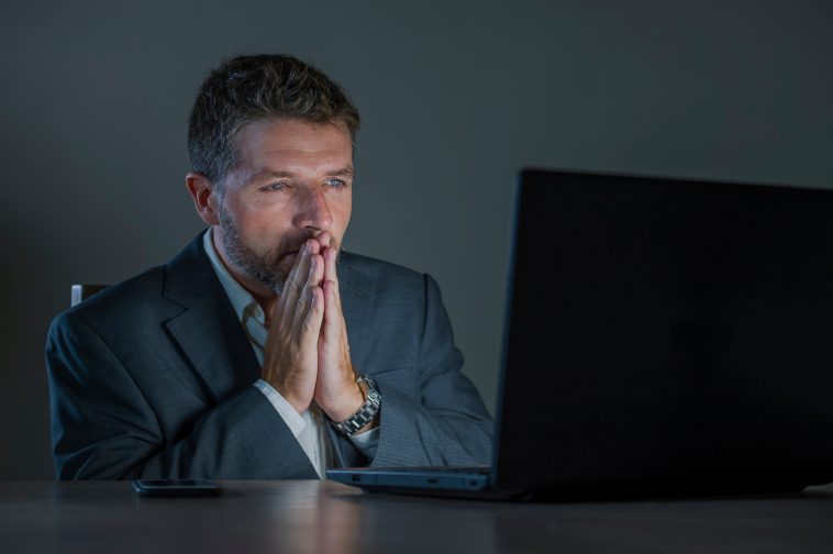 young attractive and surprised workaholic  entrepreneur man working late night using laptop computer in shock and surprise with disbelief face expression in business lifestyle concept