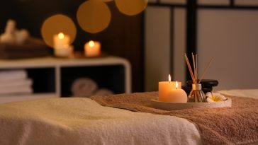 Burning candles and aromatic reed freshener on table in spa salon, space for text