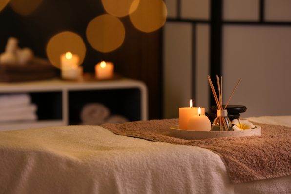 Burning candles and aromatic reed freshener on table in spa salon, space for text