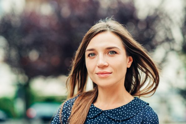 Outdoor portrait of attractive young woman with long brown hair