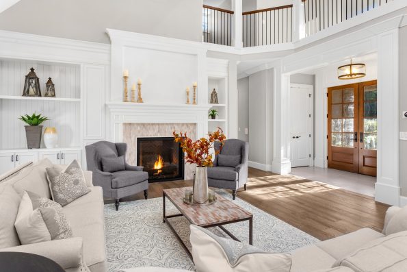 Beautiful living room in new traditional style luxury home. Features vaulted ceilings, fireplace with roaring fire, and elegant furnishings.