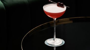 Fresh cocktail glass on glass table in night club restaurant. Alcohol cocktail drink, close-up. Retro alcoholic beverage