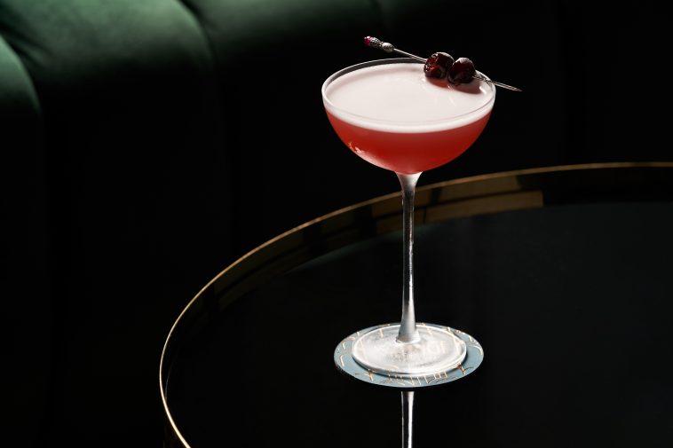 Fresh cocktail glass on glass table in night club restaurant. Alcohol cocktail drink, close-up. Retro alcoholic beverage