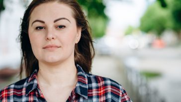 Beautiful girl, plus size looks straight into the camera, on a background of the city