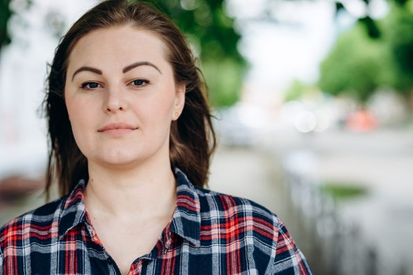 Beautiful girl, plus size looks straight into the camera, on a background of the city