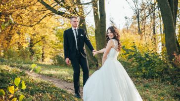 Sunshine portrait of happy bride and groom outdoor in nature location at sunset. Warm summertime. Happy couple with a beautiful bouquet of flowers. Wedding photo. Couple in love. Autumn wedding