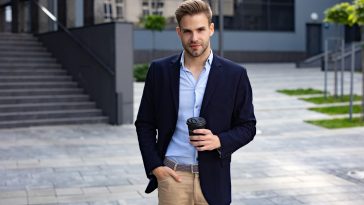 Portrait of handsome smiling man in casual wear. Successful young businessman.Young man standing on the city street near business center.