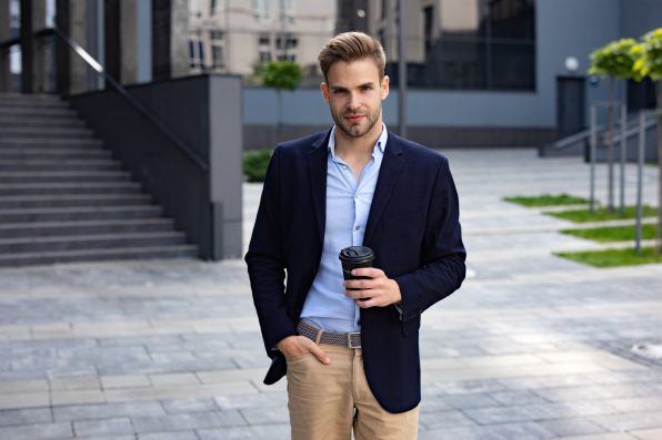 Portrait of handsome smiling man in casual wear. Successful young businessman.Young man standing on the city street near business center.