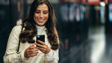 Beautiful young woman using a smartphone while in the subway waiting for her transportation