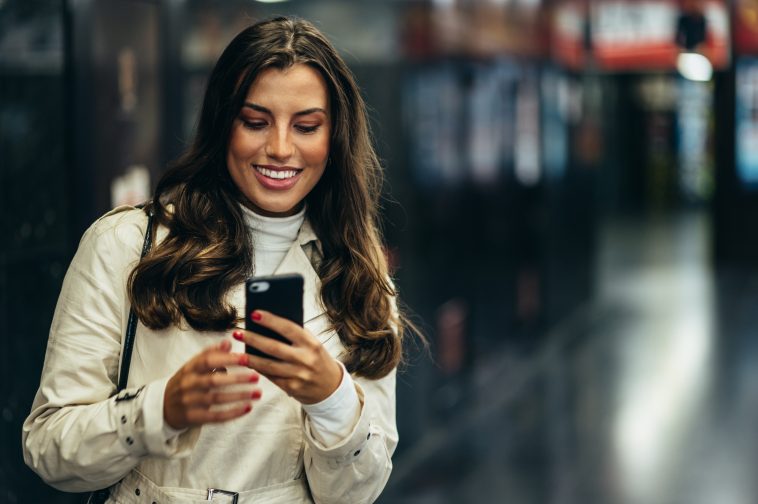 Beautiful young woman using a smartphone while in the subway waiting for her transportation