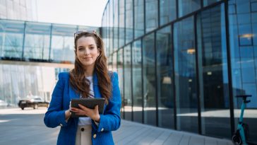 Successful woman real estate agent holding tablet and looking to camera. Business centre location. High quality photo